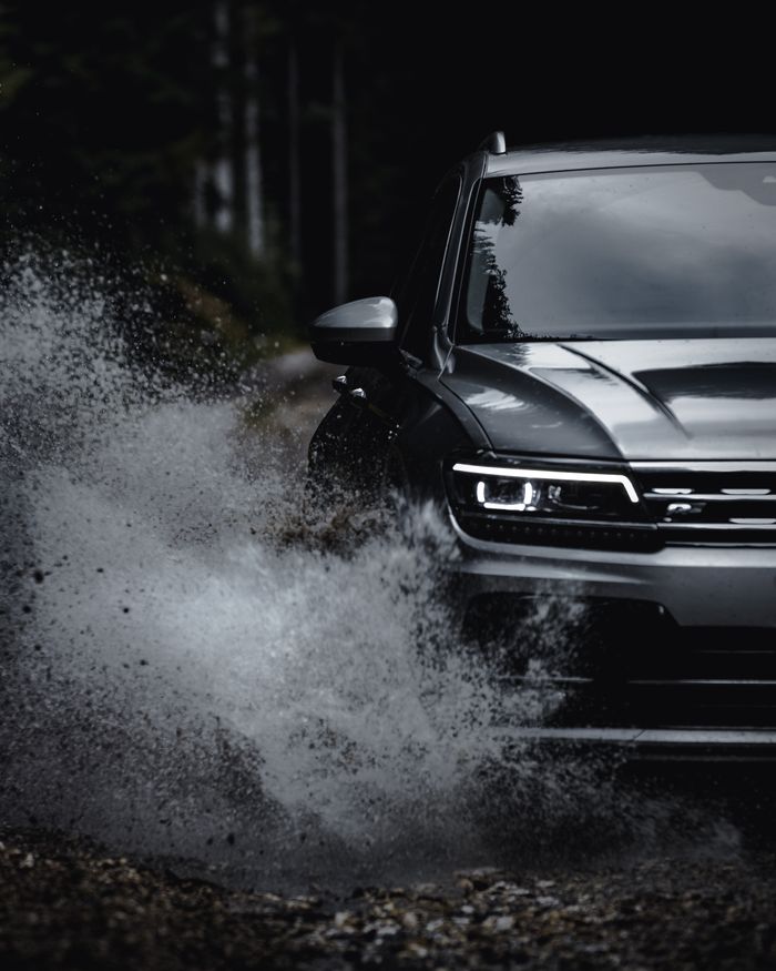 Capture of a car splashing through a puddle on a forest road, showcasing dynamic motion and adventure.